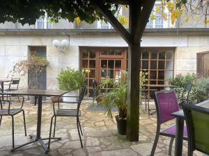 een patio met een tafel en stoelen en een gebouw bij Le Grand Monarque Donzy in Donzy