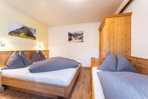 two beds in a room with wooden walls and wood floors at Landhaus Kendler in Saalbach Hinterglemm