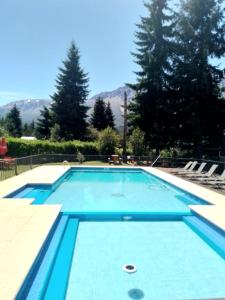 a large swimming pool with blue water at Aparts chalet Alquimia in Lago Puelo