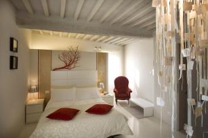 um quarto com uma cama e uma cadeira vermelha em Palazzo Bontadosi Hotel & Spa em Montefalco