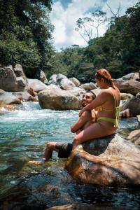 Ein Mann und eine Frau sitzen auf einem Felsen im Fluss in der Unterkunft La Perla Negra - Black Pearl Eco Hostel in San Rafael