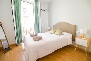 um quarto com uma grande cama branca e 2 almofadas em Apartments Olé - Tetuán em Sevilha