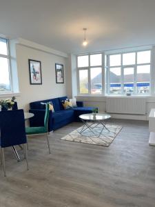 a living room with a blue couch and a table at Flitwick Luxury Apartments in Flitwick