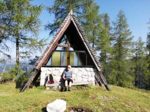 a woman sitting in front of a triangular house at Ferienwohnung Schmaranzer in Gosau