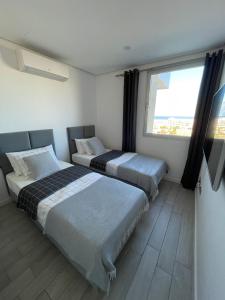 two beds in a room with a large window at Ocean Garden Sunset Apartment - heated swimming pool Free WIFI in Adeje