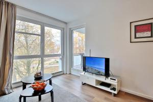 salon z telewizorem z płaskim ekranem i dużymi oknami w obiekcie Strandglück Haus A Strandglück Appartement 12A w mieście Scharbeutz