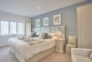a bedroom with a large white bed and a chair at 5 The Sands in Polzeath