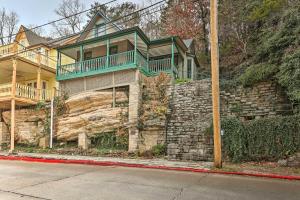 a large house with a green balcony on a stone wall at Cozy Eureka Springs Cottage, Walk to Dtwn! in Eureka Springs