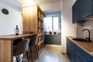 a kitchen with blue cabinets and a counter with stools at Touchdown Apartment near Bucharest Airport in Otopeni