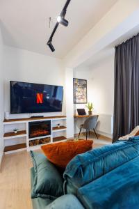 a living room with a blue couch and a tv at Touchdown Apartment near Bucharest Airport in Otopeni