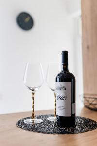 a bottle of wine sitting next to a wine glass at Touchdown Apartment near Bucharest Airport in Otopeni +26 photos