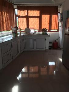 eine Küche mit weißen Schränken und einem großen Fenster in der Unterkunft tina house in Bel Ombre
