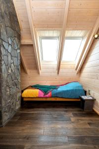 a bed in a wooden room with two windows at Houten Vakantiewoning "ReisnaarPolen" inclusief royaal ontbijt, sauna en gids in Czarna Góra
