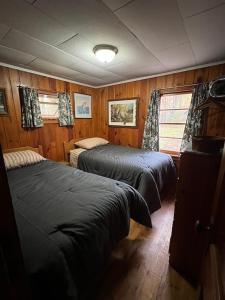 2 letti in una camera con pareti in legno e pavimenti in parquet di Red Tree Resort LLC a Phillips