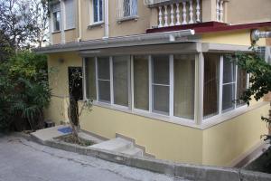 Casa amarilla con ventanas y porche en Apartment Voykova 23 en Sochi