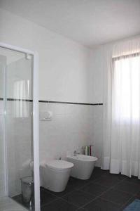 a white bathroom with a toilet and a shower at Grillo Casa Vacanze in Tessera