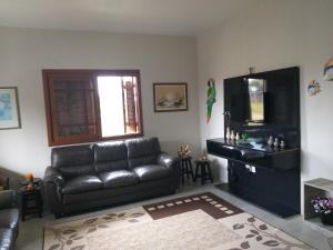 sala de estar con sofá de cuero y TV en Recanto da Praia Paraíso, en Torres