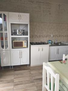 cocina con armarios blancos y microondas en Recanto da Praia Paraíso, en Torres