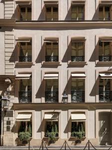 a facade of a building with windows and potted plants at MARQUIS Faubourg Saint-Honoré Relais & Châteaux in Paris