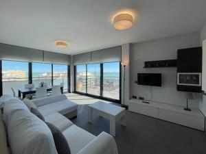 a living room with white couches and a television at Apartamentos la Volta Aguamarina in Peñíscola