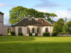 una casa con un césped verde delante de ella en The Coach House at Stewart Hall, en Rothesay