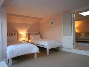 1 dormitorio con 2 camas y espejo en The Coach House at Stewart Hall, en Rothesay