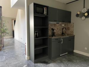 a kitchen with a black cabinet with a microwave at Verblijf in loft van luxe villa de Vossenberg in Etten-Leur