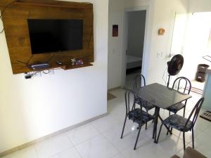 comedor con mesa, sillas y TV en Residencial Praia dos Corais, en Santa Cruz Cabrália