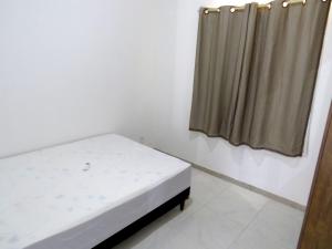 Habitación pequeña con cama y cortina en Residencial Praia dos Corais, en Santa Cruz Cabrália