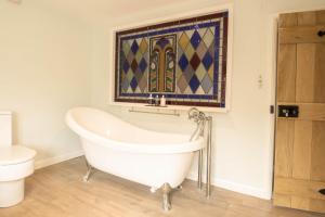 a bathroom with a tub and a toilet and a window at 1 School Lane in Malton +34 photos