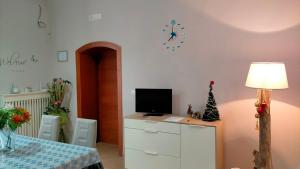 Habitación con escritorio, TV y reloj en la pared. en ONDA MARE Holiday Home, en Giovinazzo