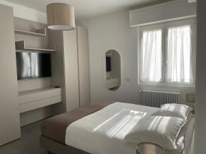 a white bedroom with a bed and a tv at Domus Pyrus Apartments in Pero