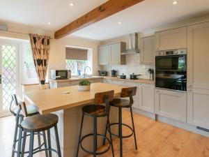 a kitchen with a wooden island with bar stools at Riverside Cottage-uk41439 in Brandon