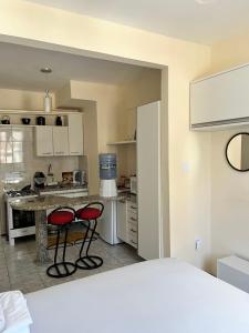 a kitchen with two red chairs in front of a counter at Stúdio Beira Mar in Fortaleza
