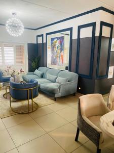 a living room with a blue couch and chairs at Abusar Apartment in Boksburg