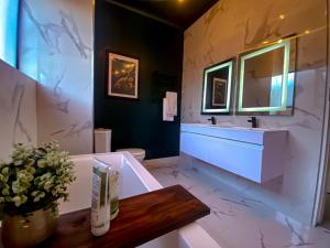 a bathroom with a tub and a sink and a mirror at Abusar Apartment in Boksburg +25 photos