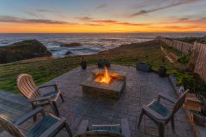 a patio with a fire pit and chairs and the ocean at Puffin's Perch in Fort Bragg