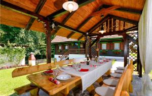 a dining table and chairs under a wooden pavilion at Cozy Home In Kupljenovo With Heated Swimming Pool in Kupljenovo