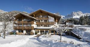 un gran edificio de madera con nieve en el suelo en Hotel Stefaner en Tires