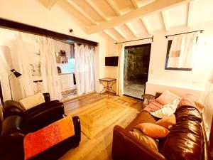 a living room with a leather couch and a window at Casa les bambous in Nîmes