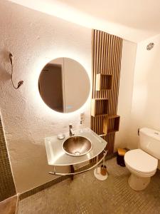 a bathroom with a sink and a toilet and a mirror at Casa les bambous in Nîmes