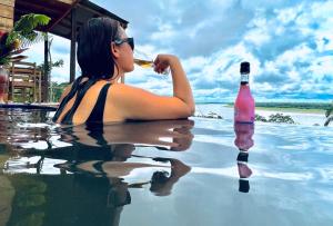 uma mulher sentada numa piscina a beber um copo de vinho em Reserva Natural Natura Park em Puerto Nariño