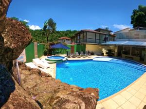 a large swimming pool in front of a house at Recanto Vicks Flats in Ilhabela