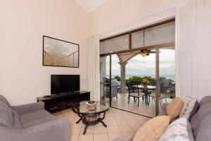 ein Wohnzimmer mit einem Sofa und einem TV in der Unterkunft Sunrise 48- 3 Bedroom Ocean View Penthouse Condo in Tamarindo