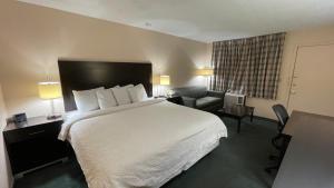 una habitación de hotel con una cama grande y una silla en Slumber Inn Harrisonville, en Harrisonville