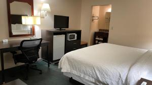 a hotel room with a bed and a desk with a tv at Slumber Inn Harrisonville in Harrisonville