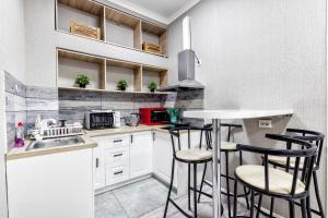 Комфортная квартира в центре города في أستانا: مطبخ مع خزائن بيضاء وكراسي البار