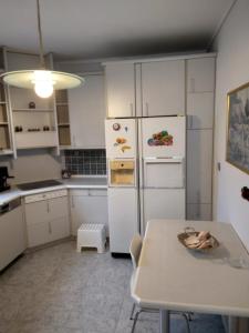uma cozinha com armários brancos, uma mesa e um frigorífico em Villa in Panorama, Thessaloniki, with a swimming pool. Host: Mr. George em Tessalônica
