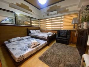 a bedroom with two beds and a chair at CedarPeak215 in Baguio