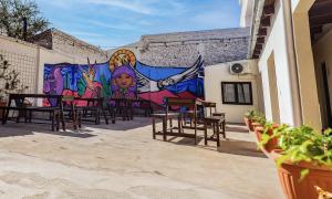 une fresque murale sur le côté d'un bâtiment avec des tables et des chaises dans l'établissement HOSTEL PUNTO RAMIREZ, à Salta